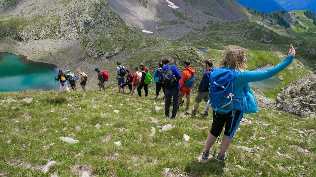 Groupe mixte de randonneurs marchant sur un sentier de montagne avec différents rythmes